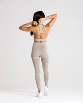 المنظر الخلفي لامرأة ترتدي بنطال ضيق Move Seamless من WOMEN'S BEST باللون البني الرمادي مارل، مما ينضح بالراحة والأناقة.